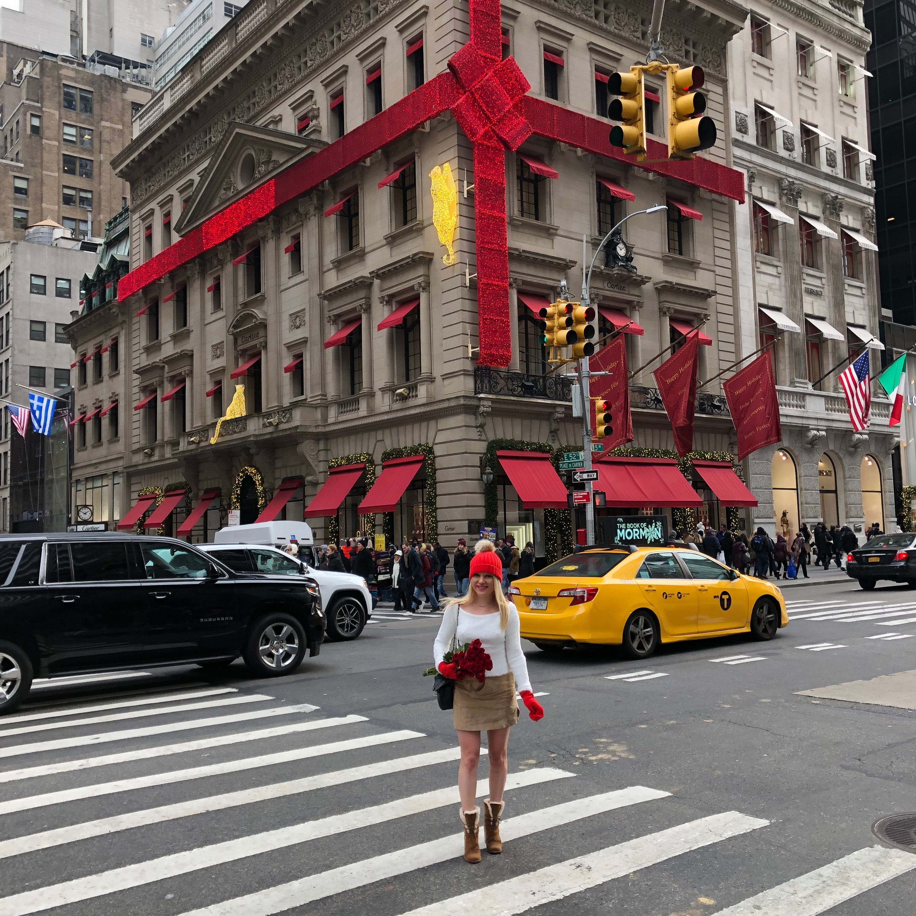 NYC building wrapped in a big sparkly red bow, red winter accessories, white fuzzy sweater